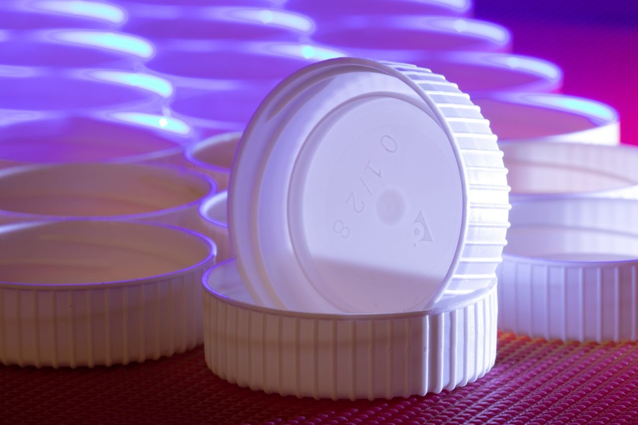 heros-img Aesthetic arrangement of white plastic lids with striking blue and purple lighting.