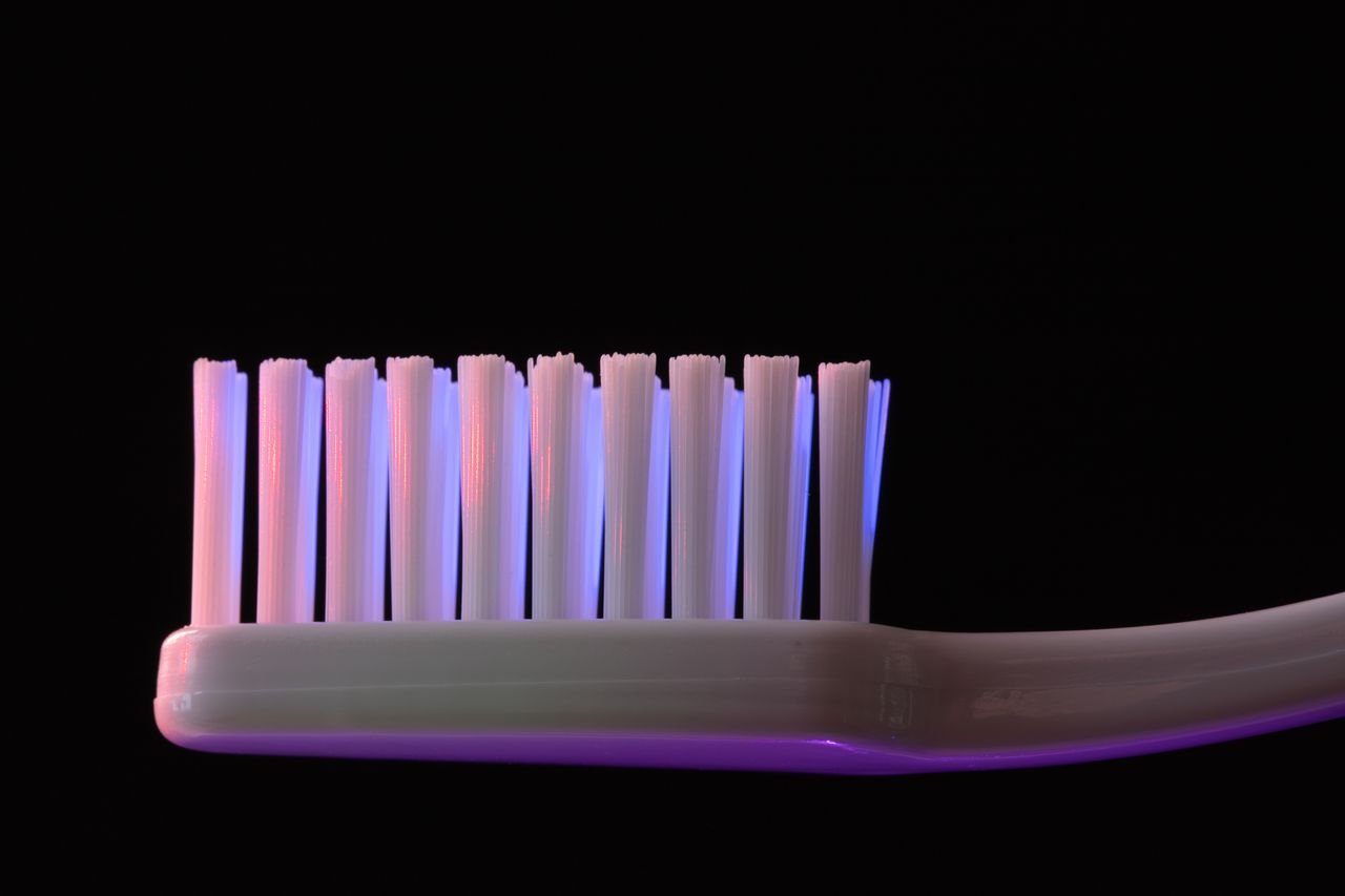 Detailed close-up of a toothbrush bristles under colorful lighting against a black background.