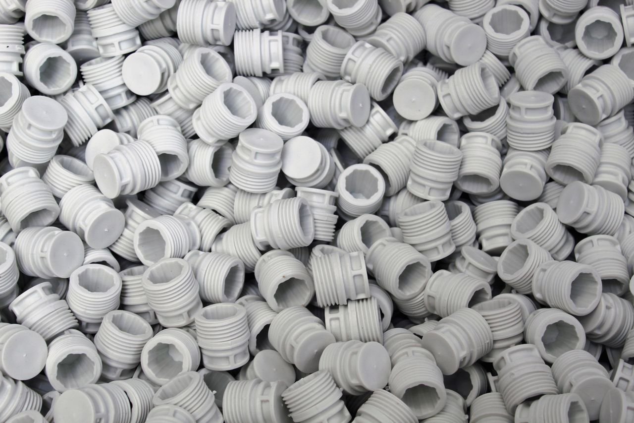 about-us-01 A high-quality image of numerous white plastic screw caps piled together, showcasing industry production.